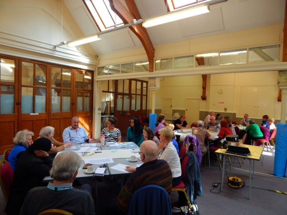 people gathered round tables in a village hall